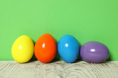 Easter eggs on white wooden table against green background