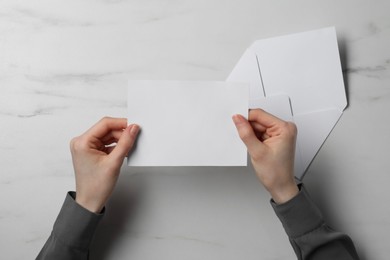 Photo of Woman with blank card at marble table, top view. Space for text