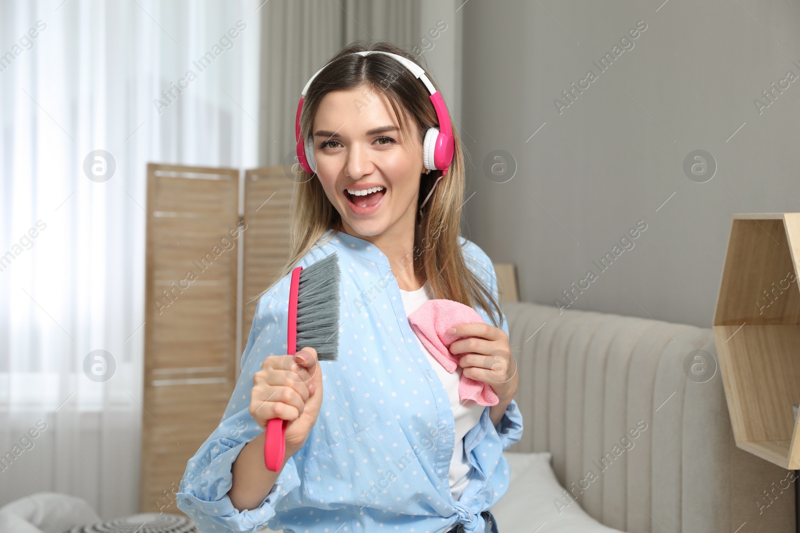 Photo of Woman in headphones with hairbrush singing at home