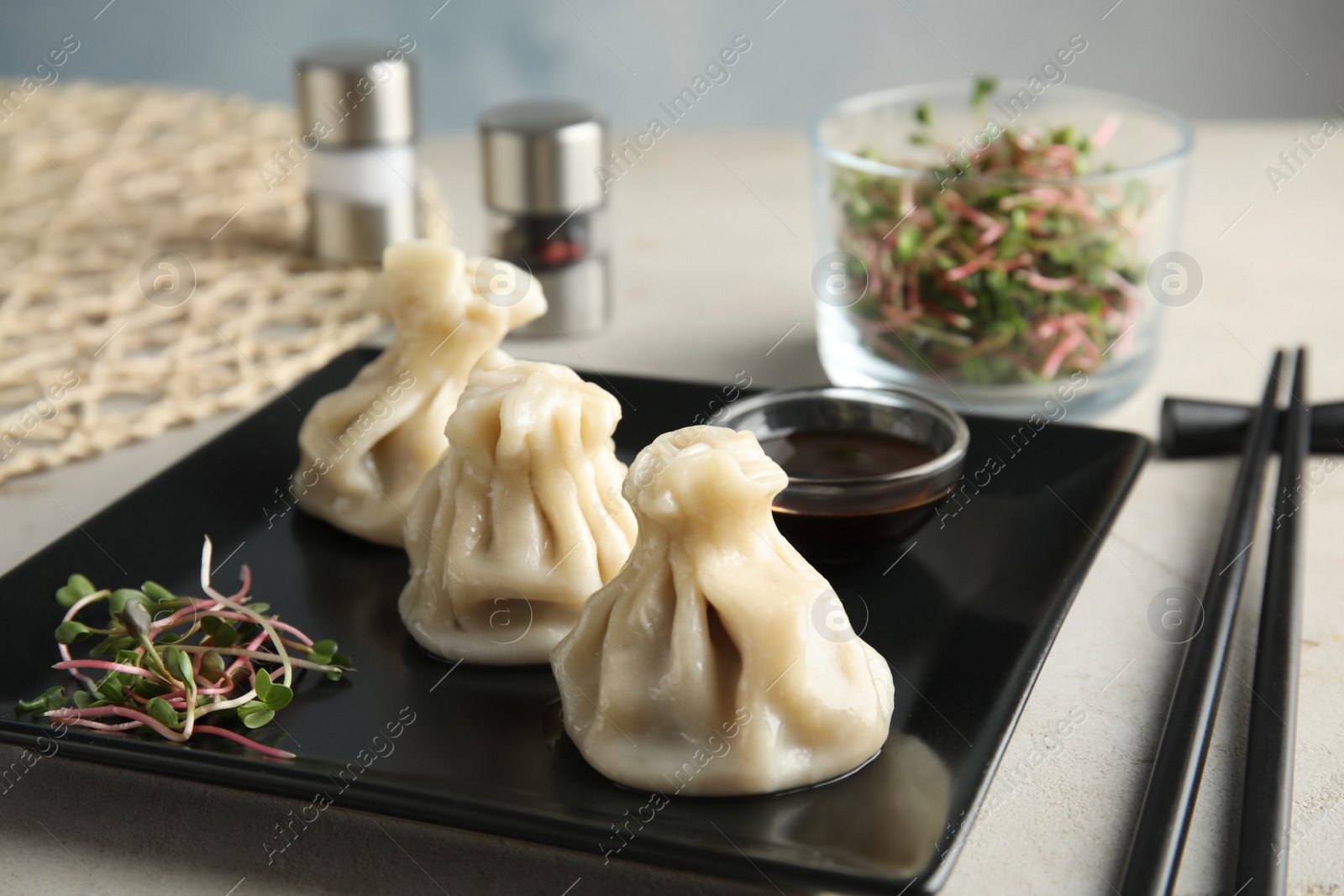 Photo of Plate with tasty baozi dumplings, sprouts and soy sauce on table