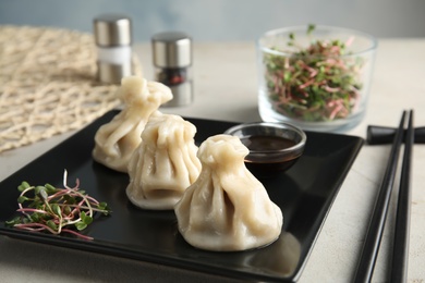 Photo of Plate with tasty baozi dumplings, sprouts and soy sauce on table