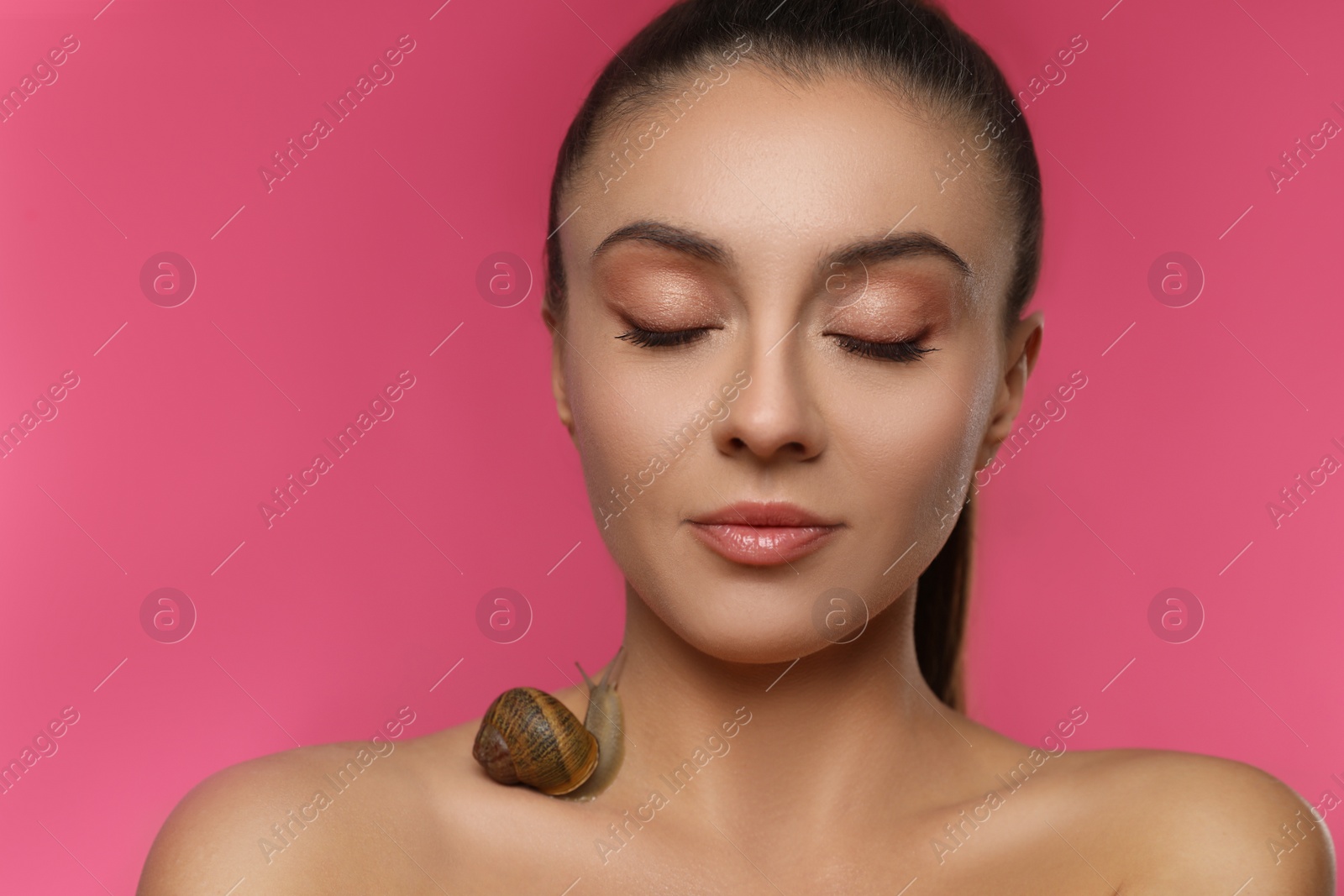 Photo of Beautiful young woman with snail on her body against pink background