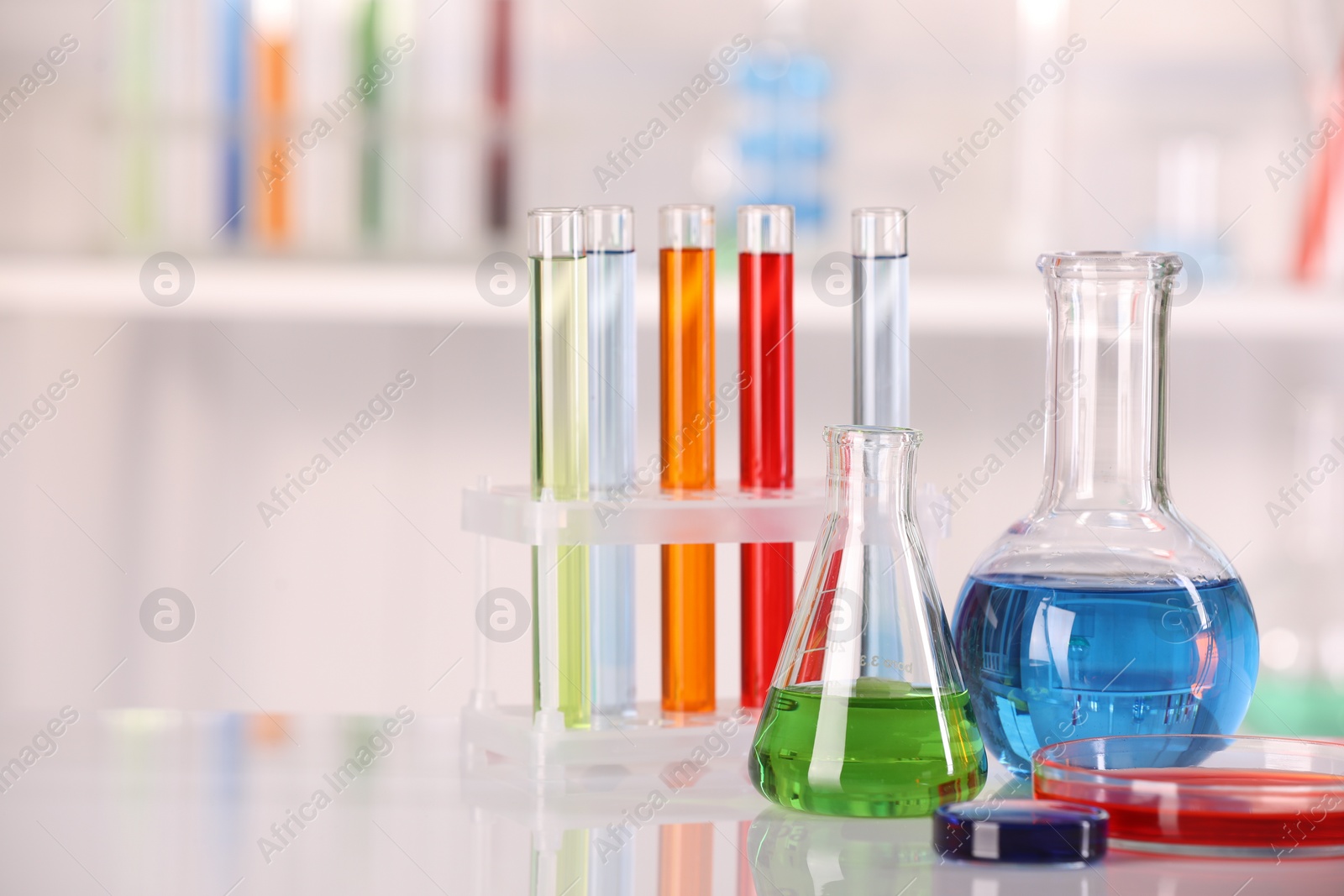 Photo of Laboratory analysis. Different glassware with liquids on white table against blurred background. Space for text