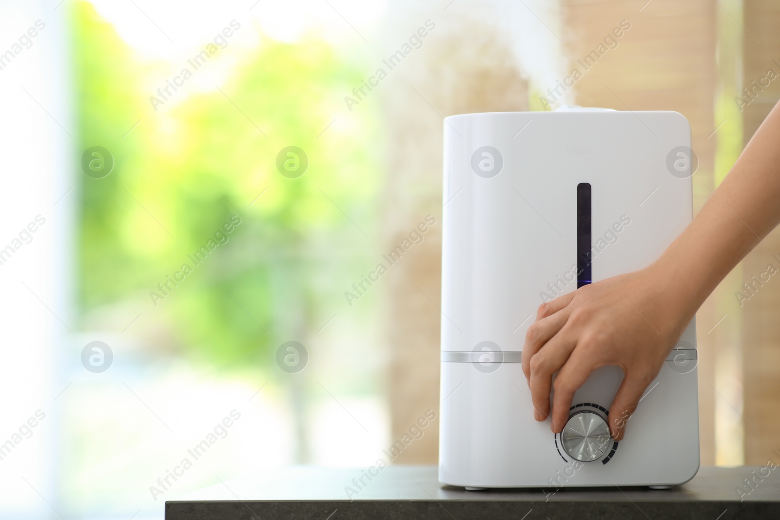 Photo of Woman turning on air humidifier indoors, closeup. Space for text