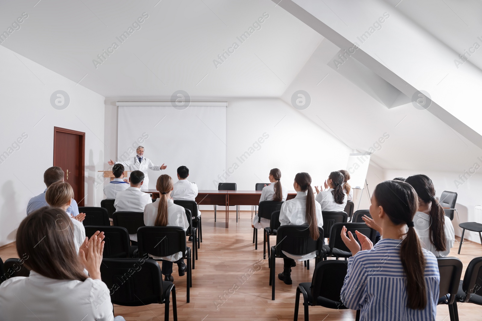 Photo of Senior doctor giving lecture to audience during medical conference in meeting room