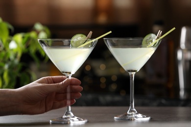 Woman holding glass of martini at bar counter, closeup