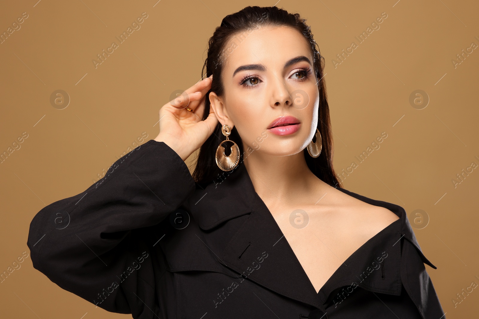 Photo of Portrait of young woman with beautiful makeup on light brown background