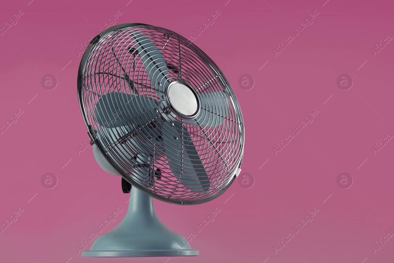 Photo of Modern electric fan on pink background. Space for text