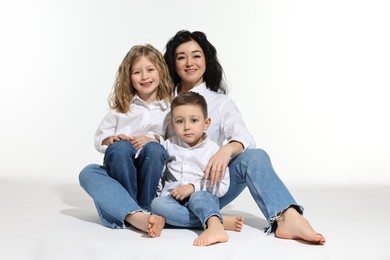 Photo of Little children with their mother sitting together on white background