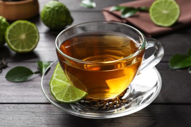 Glass cup of tasty bergamot tea on wooden table, closeup