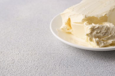 Plate with tasty homemade butter on white textured table, closeup. Space for text