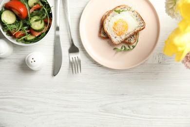 Photo of Delicious breakfast with fried egg, toasted bread and arugula served on white wooden table, flat lay. Space for text