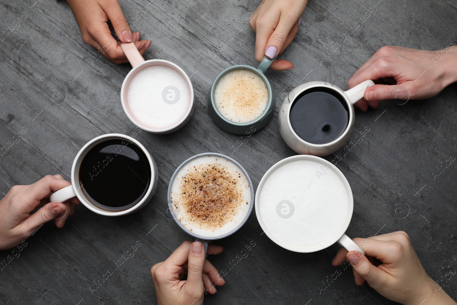 Photo of People holding different cups with aromatic hot coffee at grey table, top view