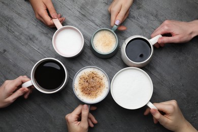 People holding different cups with aromatic hot coffee at grey table, top view