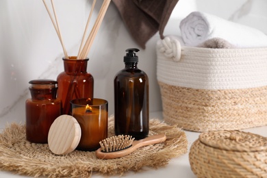 Photo of Soap dispenser, air reed freshener and burning candle on countertop in bathroom