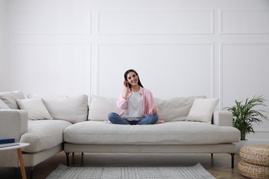 Woman with headphones on sofa in living room