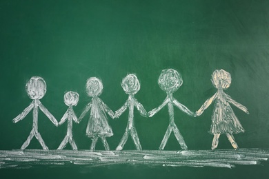 Photo of Drawing of people holding hands together on chalkboard. Unity concept