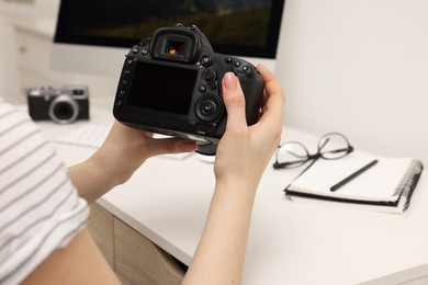 Photographer with camera at white table indoors, closeup