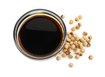 Photo of Tasty soy sauce in bowl and soybeans isolated on white, top view