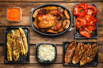 Plastic containers with different dishes on wooden table, flat lay. Food delivery service