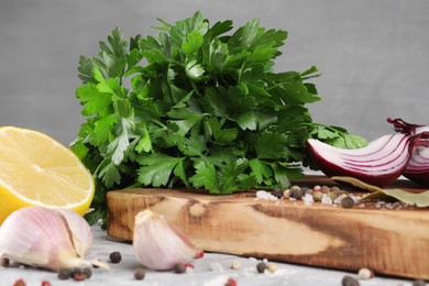 Bunch of fresh parsley, lemon, onion, garlic and spices on grey textured table