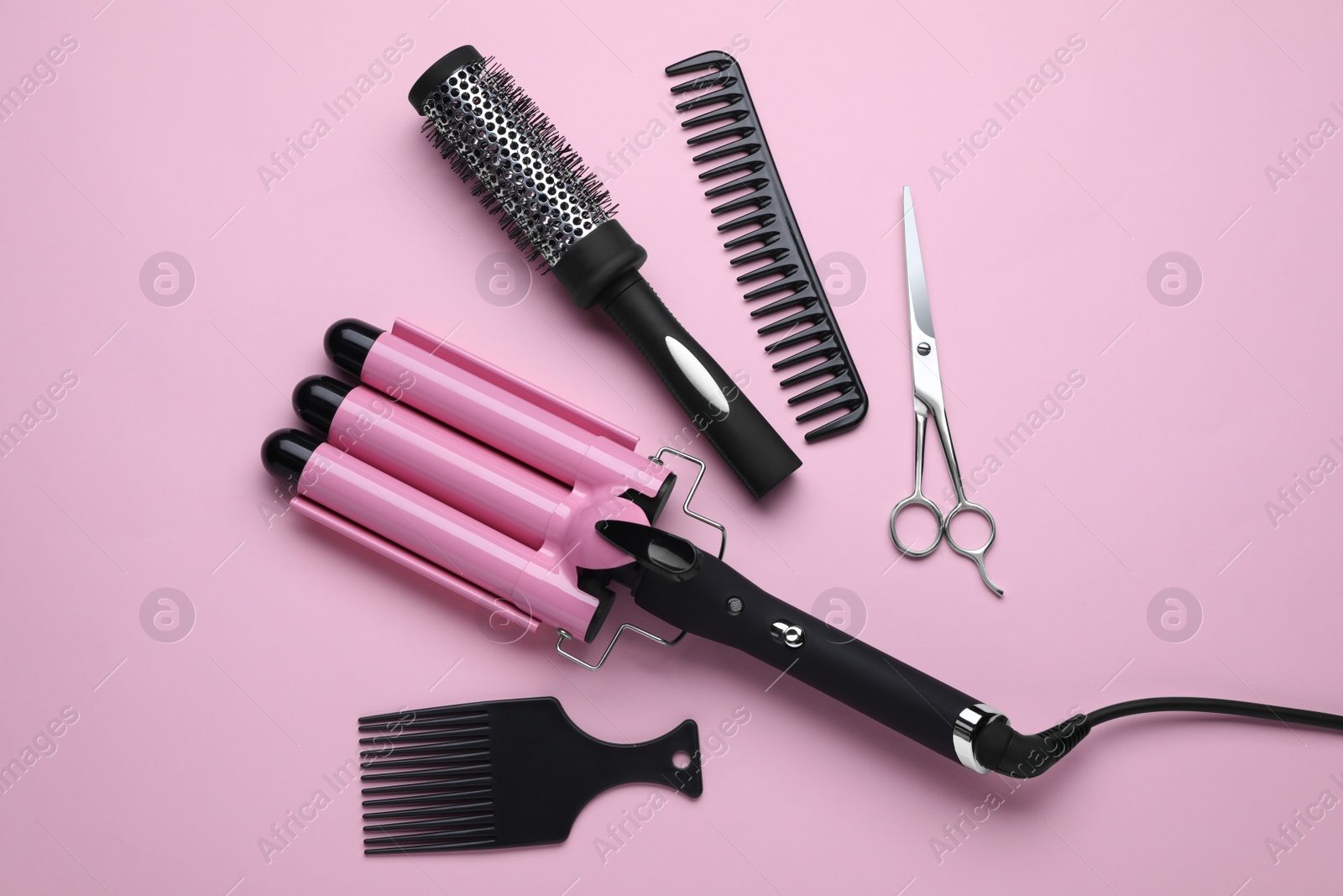 Photo of Flat lay composition of professional hairdresser tools on pink background