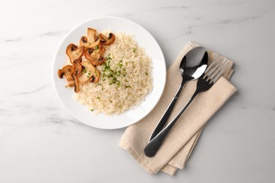 Photo of Delicious rice with parsley and mushrooms served on white marble table, flat lay