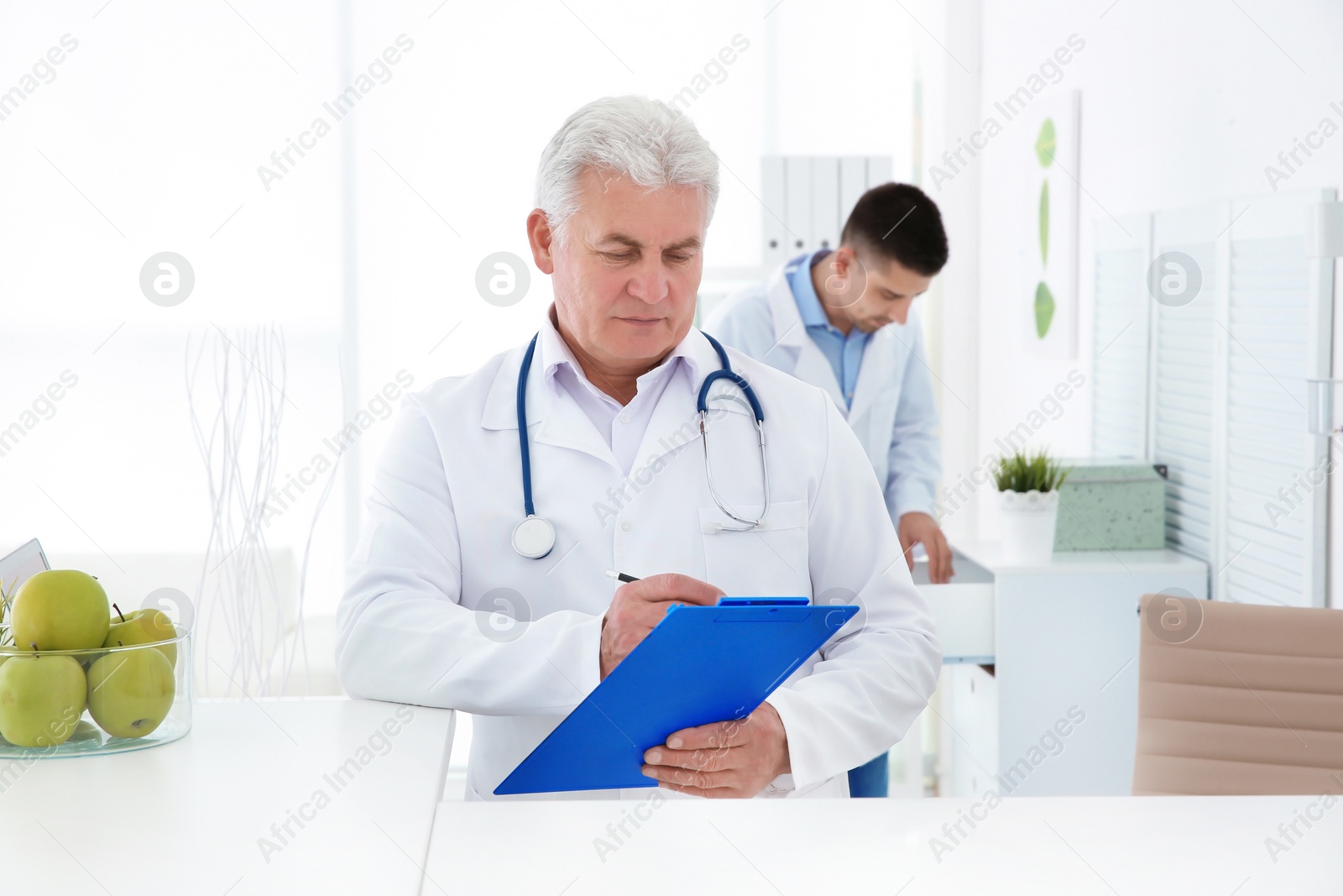 Photo of Senior male doctor working at reception desk in hospital