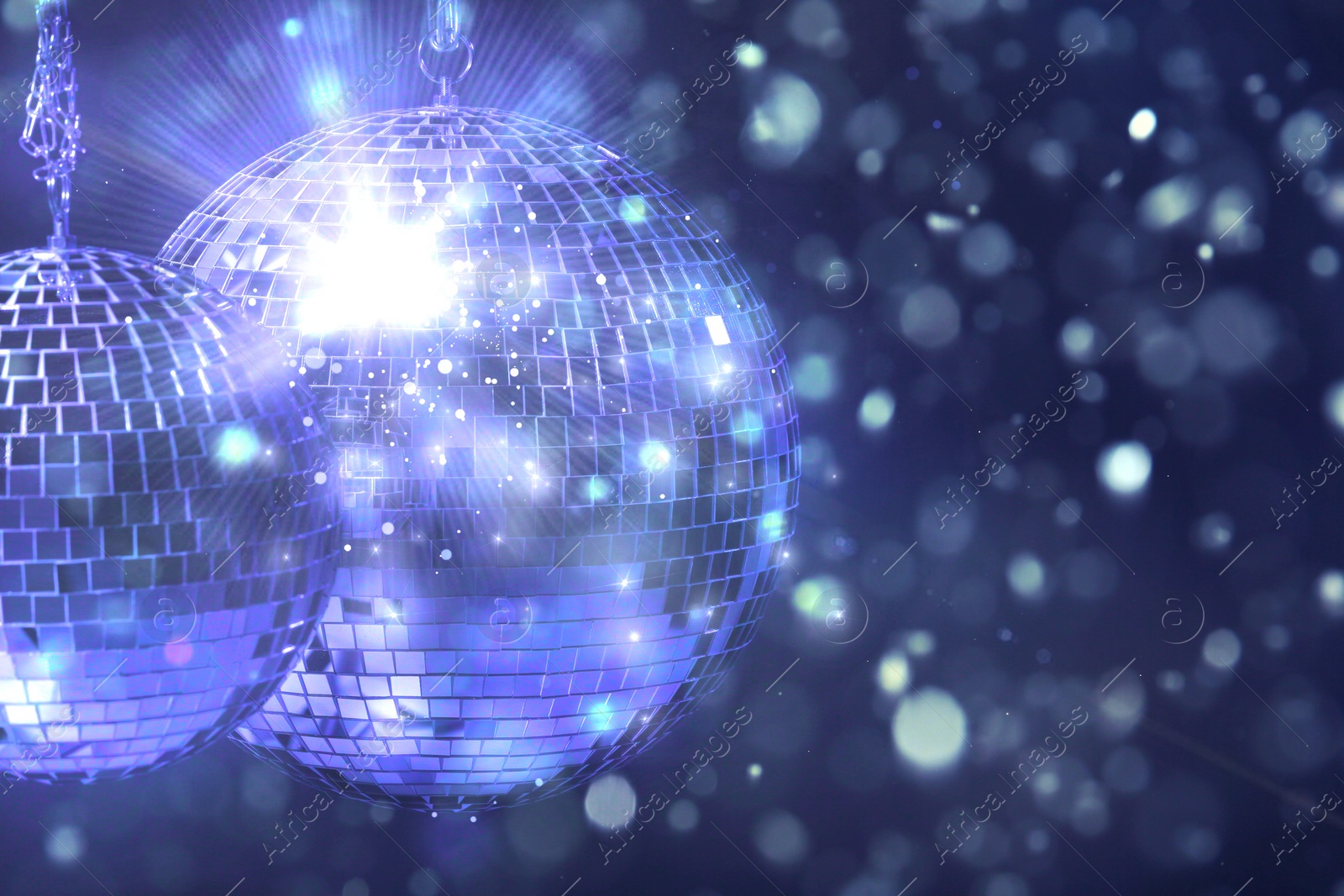 Image of Shiny disco balls under lights on color background, space for text. Bokeh effect