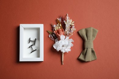 Wedding stuff. Stylish boutonniere, bow tie and cufflinks on brown background