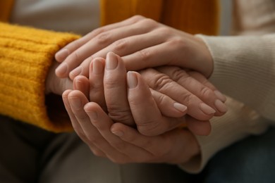 Photo of Young and elderly women holding hands together, closeup