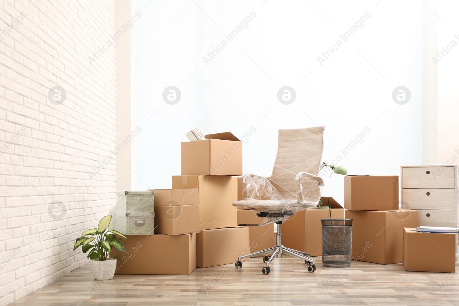 Photo of Moving boxes and stuff near white brick wall in room