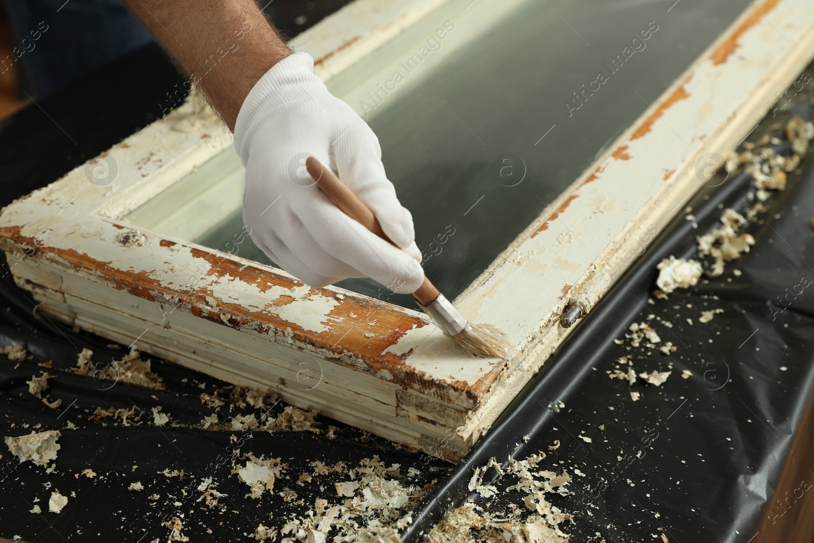 Photo of Man repairing old damaged window at table indoors, closeup