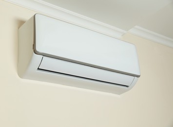 Modern air conditioner on white wall indoors