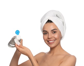 Young woman pouring micellar water onto cotton pad on white background