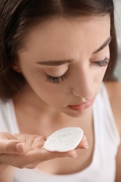 Photo of Young woman holding cotton pad with fallen eyelashes, closeup