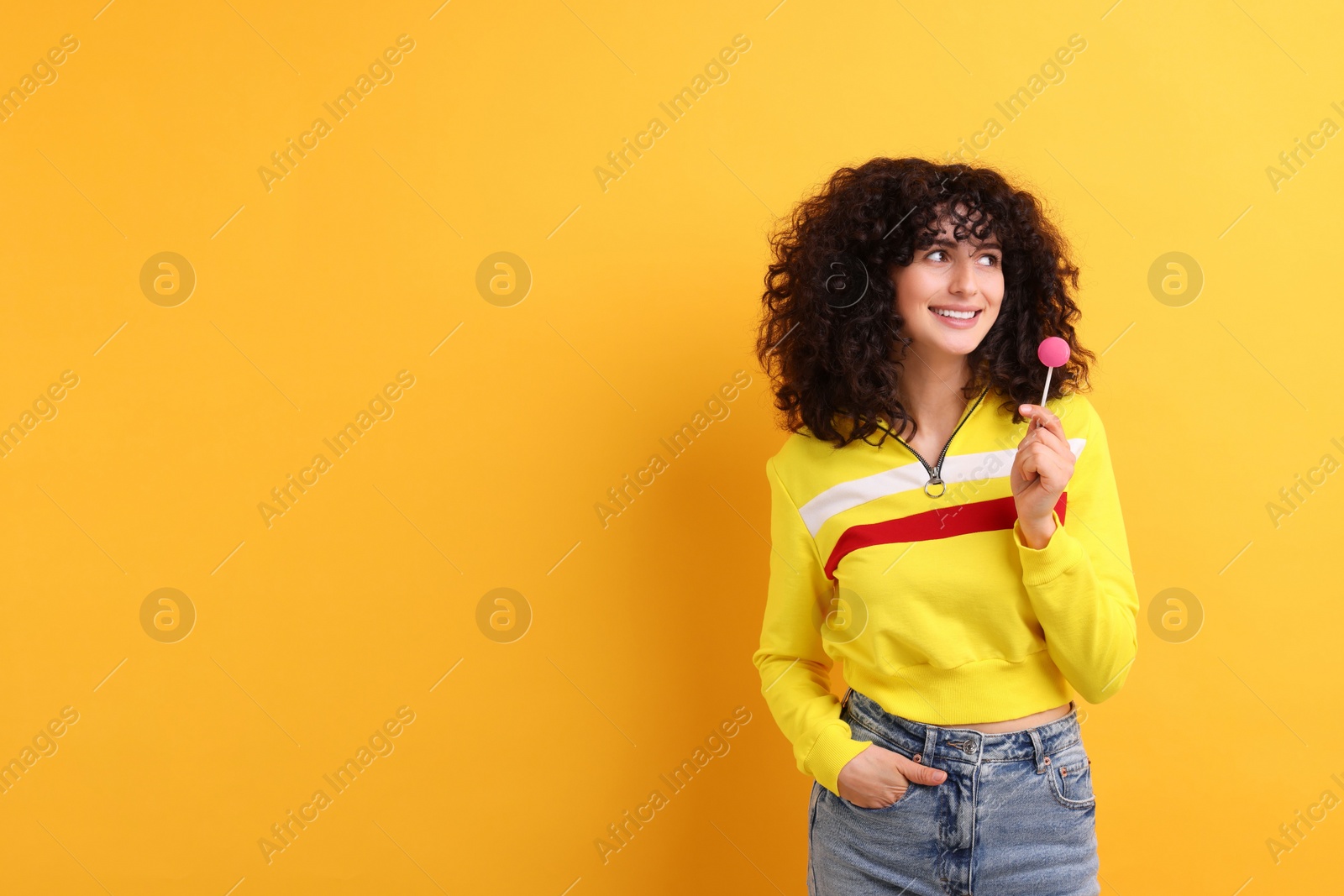 Photo of Beautiful woman with lollipop on yellow background, space for text