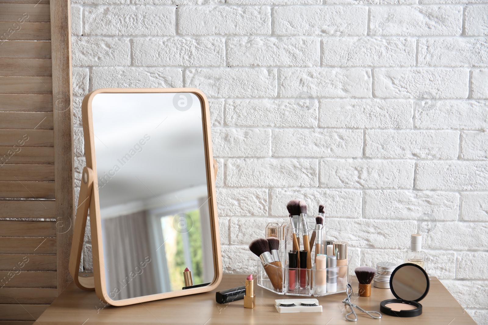 Photo of Makeup cosmetic products and tools on dressing table near brick wall with space for text