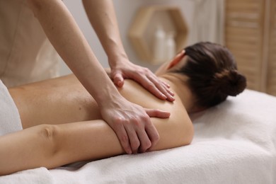 Photo of Woman receiving back massage on couch in spa salon