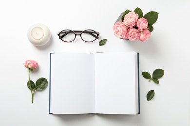 Photo of Flat lay composition with book, flowers and glasses on white background. Space for text