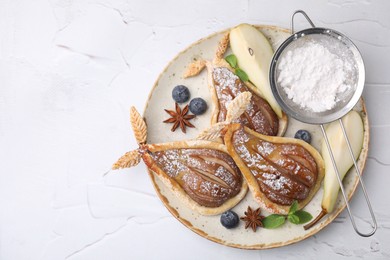 Delicious pears baked in puff pastry with powdered sugar served on white table, top view. Space for text