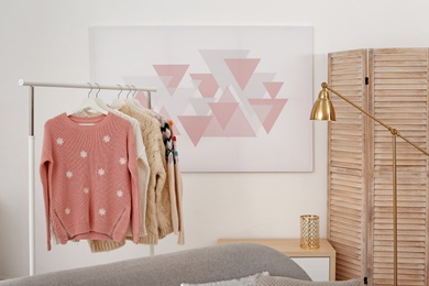 Photo of Wardrobe rack with stylish warm clothes indoors