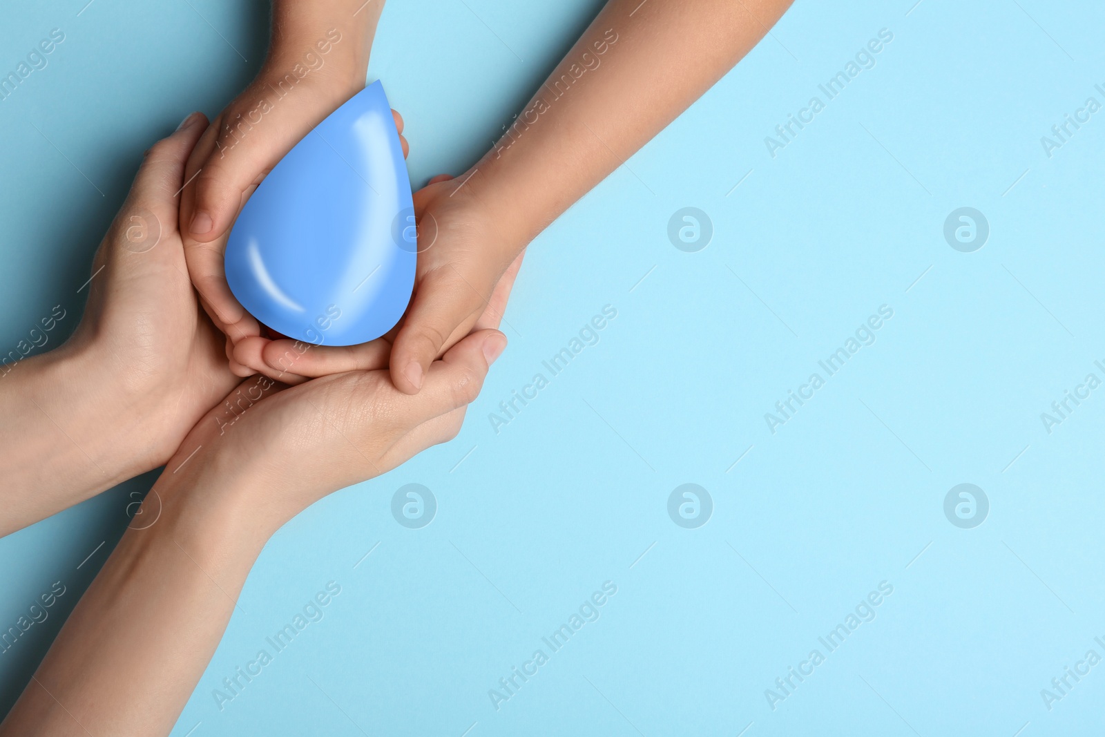 Image of Woman and her child holding water drop on light blue background, top view with space for text. Ecology protection