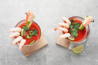 Tasty shrimp cocktail with sauce in glasses and lime on light grey table, flat lay