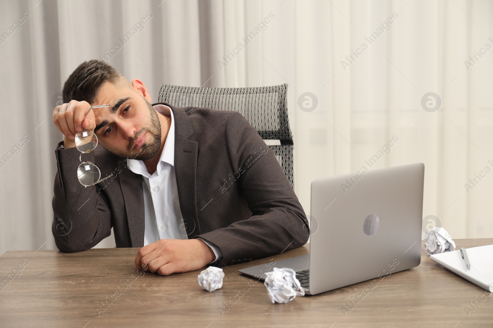 Photo of Tired sad businessman sitting at table in office