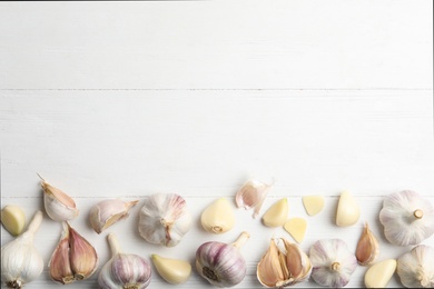 Photo of Fresh organic garlic on white wooden table, flat lay. Space for text