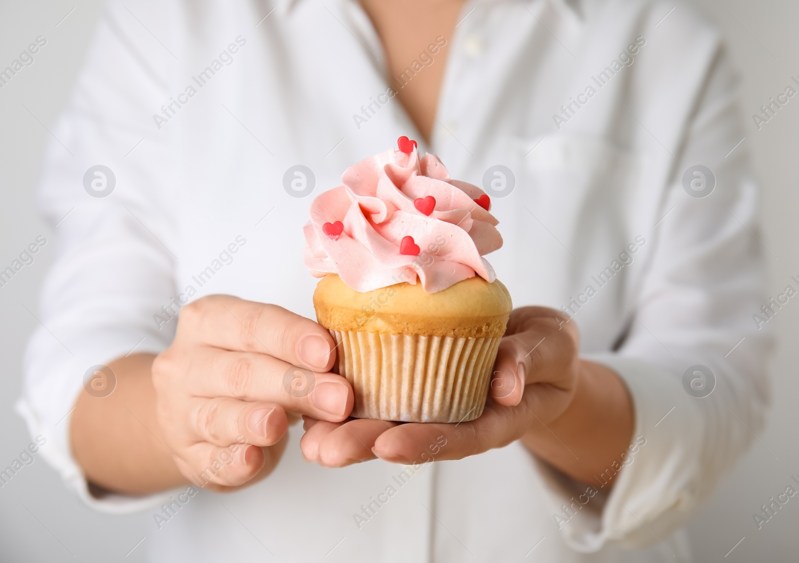 Photo of Woman holding tasty cupcake for Valentine's Day, closeup