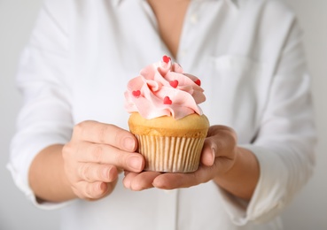 Photo of Woman holding tasty cupcake for Valentine's Day, closeup
