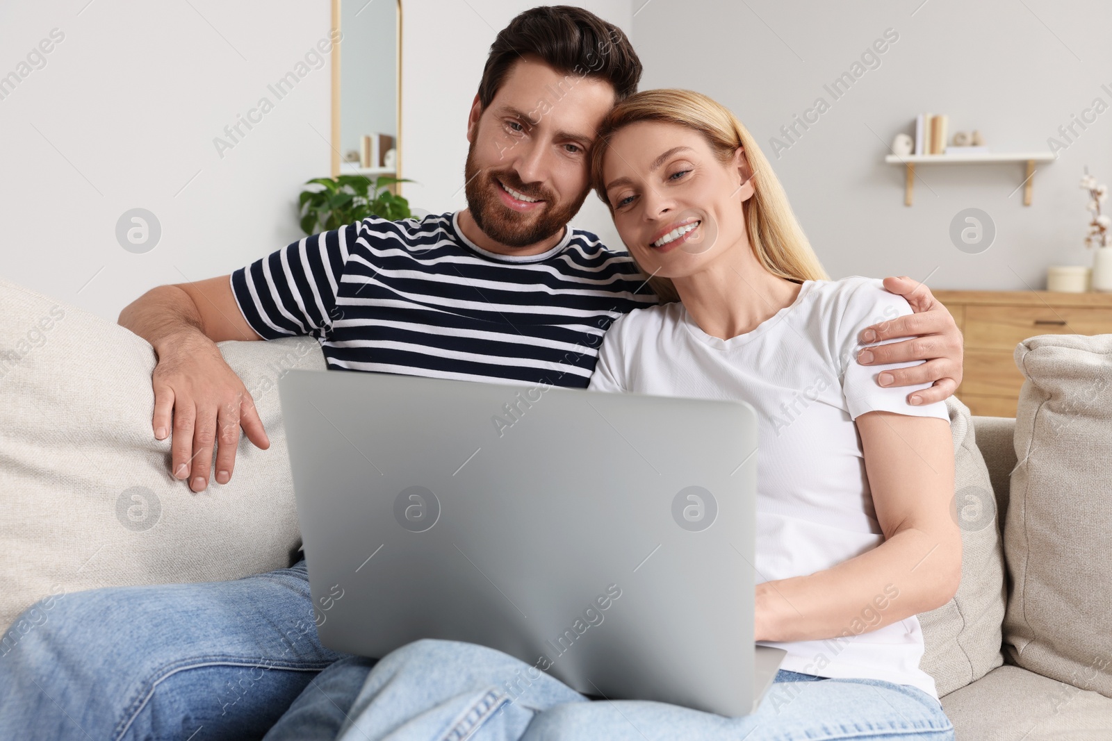 Photo of Happy couple with laptop on sofa at home