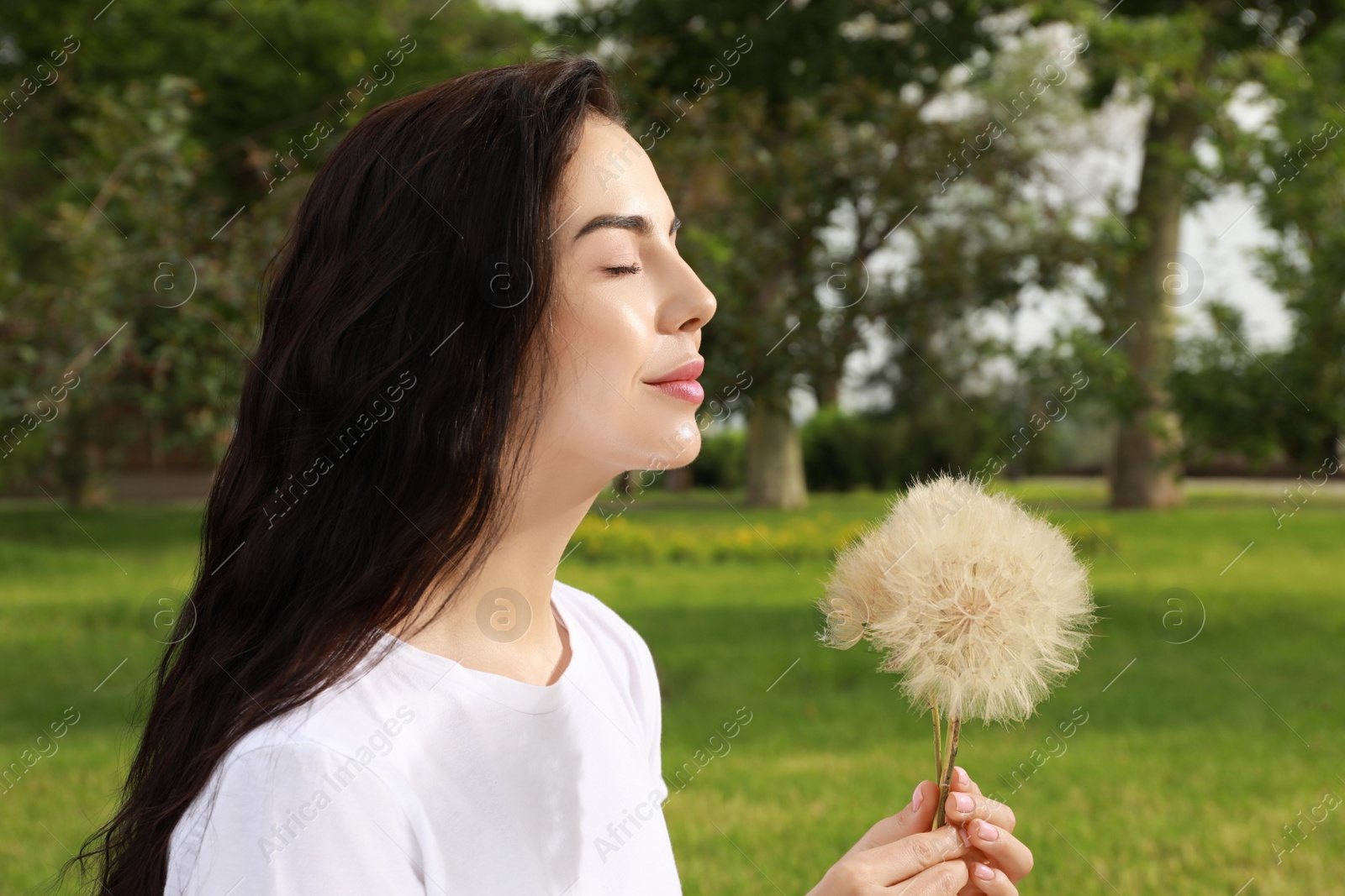 Photo of Beautiful young woman with large dandelions in park. Allergy free concept